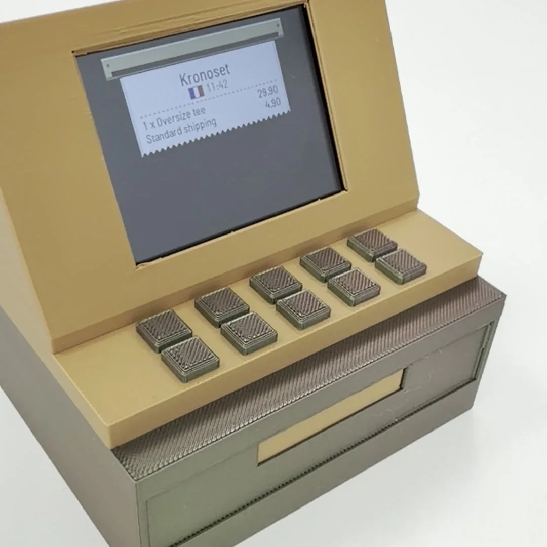The panel's screen printing a receipt: Kronoset, 11:42, 1 × Oversize tee 29.90, Standard shipping 4.90, with the paper still coming out of the roller.